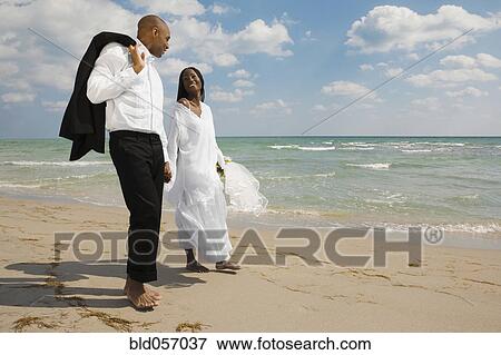 African bride and groom holding hands at beach View Large Photo Image Stock Photo - African bride and groom holding hands at beach. Fotosearch