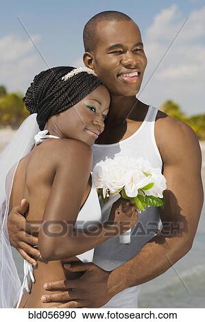 Stock Image - African bride and groom hugging. Fotosearch