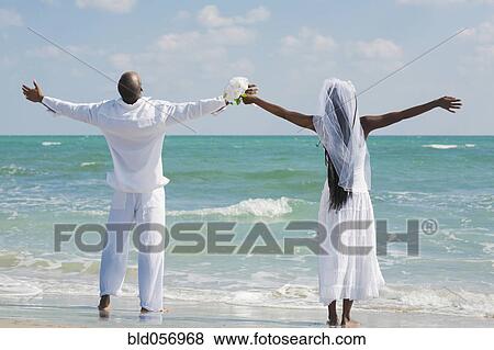 Stock Photo - African bride and groom with arms outstretched. Fotosearch