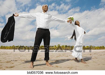 Stock Photograph - African bride and groom with arms outstretched. Fotosearch