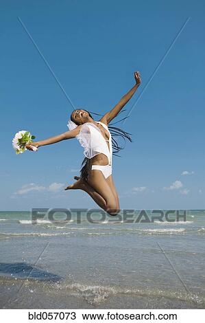 African bride jumping in ocean surf View Large Photo Image Stock Image - African bride jumping in ocean surf. Fotosearch