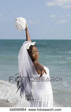 Picture - African bride looking over shoulder at beach. Fotosearch