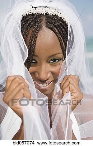 Picture - African bride pulling veil forward. Fotosearch