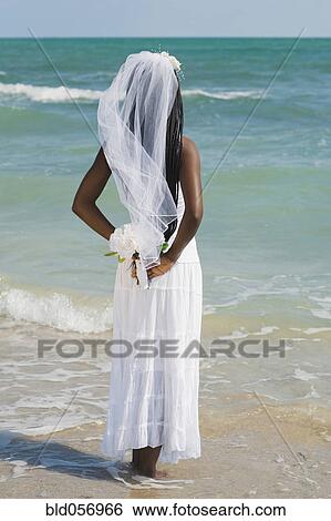 Stock Photograph - African bride standing in ocean surf. Fotosearch