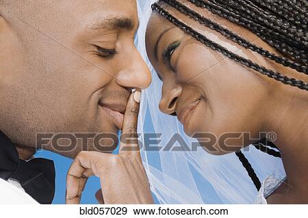 Stock Photo - African bride touching groom’s lips. Fotosearch