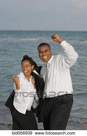 Stock Photo - African businesspeople cheering in front of water. Fotosearch