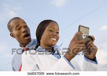 Stock Photo - African businesspeople looking at cell phone. Fotosearch