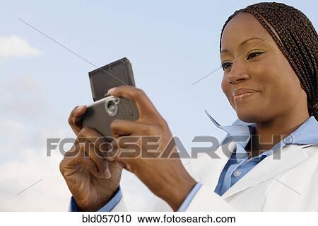 Stock Image - African businesswoman looking at cell phone. Fotosearch