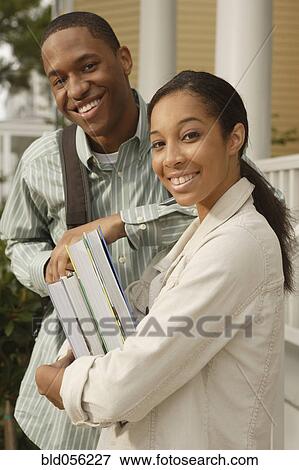 Stock Photo - African couple carrying books and backpack. Fotosearch