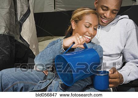 Stock Photo - African couple drinking coffee at campsite. Fotosearch