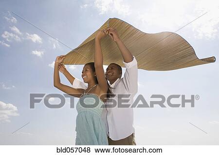 African couple holding mat in wind View Large Photo Image Stock Photo - African couple holding mat in wind. Fotosearch