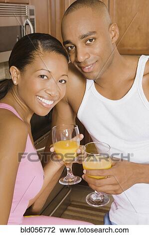 Stock Image - African couple holding orange juice. Fotosearch