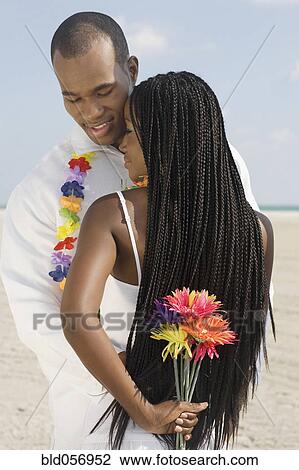 Stock Image - African couple hugging at beach. Fotosearch