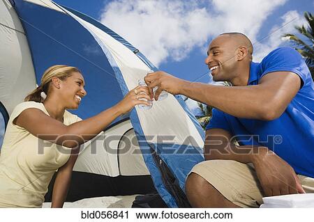Stock Image - African couple setting up tent. Fotosearch