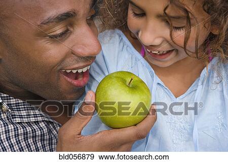 Stock Photo - African father and daughter eating apple. Fotosearch