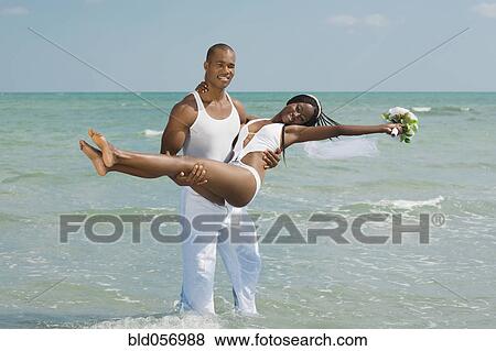 African groom carrying bride at beach View Large Photo Image Stock Photo - African groom carrying bride at beach. Fotosearch