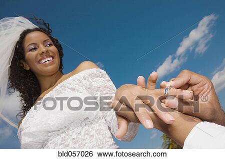 African groom putting ring on bride’s finger View Large Photo Image Stock Photograph - African groom putting ring on bride’s finger. Fotosearch