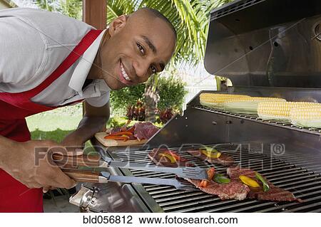 Stock Image - African man barbecuing. Fotosearch
