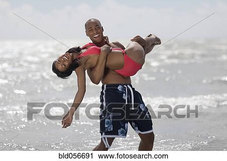 Stock Image - African man carrying girlfriend. Fotosearch