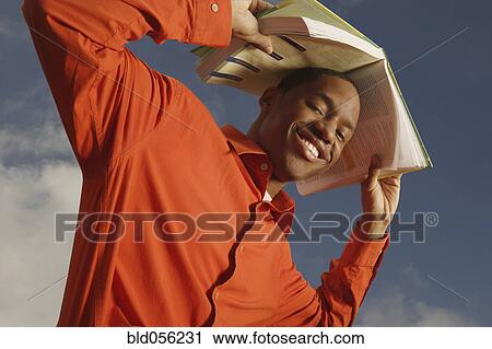 African man holding book over head View Large Photo Image Stock Image - African man holding book over head. Fotosearch