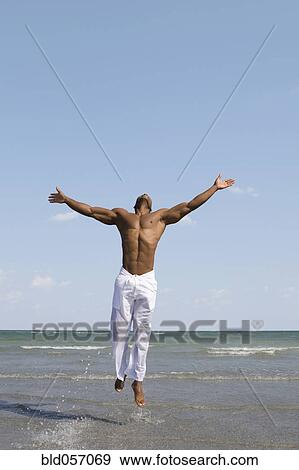 African man jumping in ocean surf View Large Photo Image Stock Photo - African man jumping in ocean surf. Fotosearch