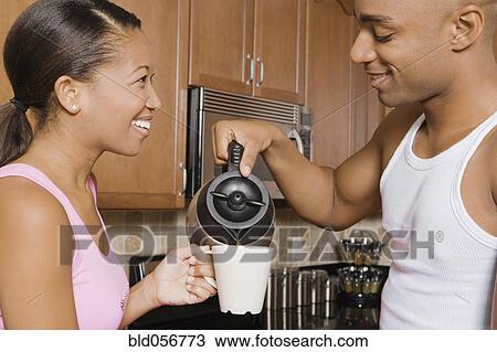 Stock Image - African man pouring coffee for wife. Fotosearch