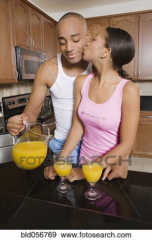 Stock Photo - African man pouring orange juice for wife. Fotosearch