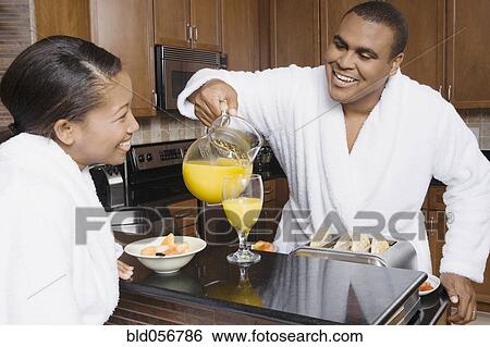 Stock Photograph - African man pouring orange juice for wife. Fotosearch