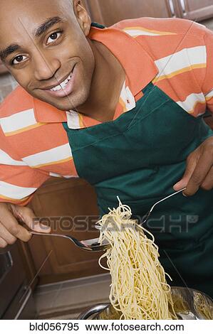 Stock Photography - African man serving spaghetti. Fotosearch
