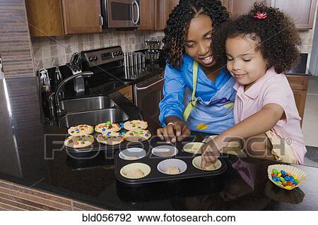 Stock Image - African mother and daughter making cupcakes. Fotosearch