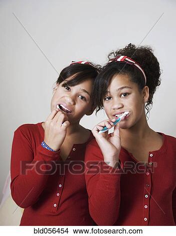Picture - African twin sisters brushing teeth. Fotosearch