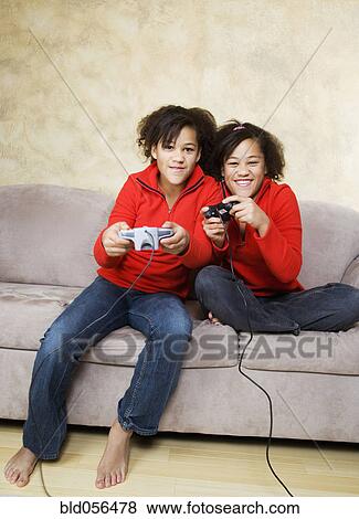 Stock Photo - African twin sisters playing video games. Fotosearch