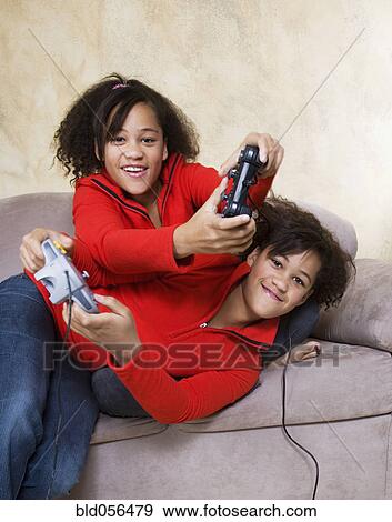 Stock Photo - African twin sisters playing video games. Fotosearch