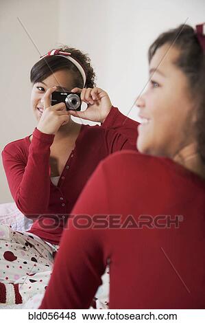 Stock Photo - African twin sisters taking photograph. Fotosearch