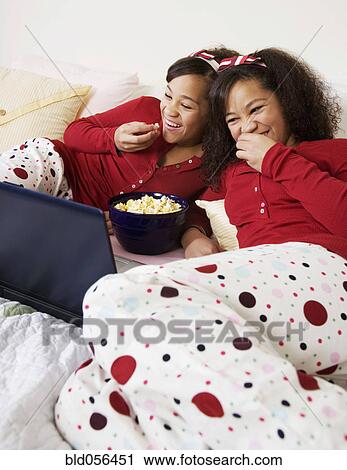 Stock Image - African twin sisters watching movie. Fotosearch