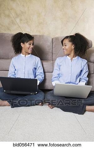 Stock Image - African twin sisters with laptops. Fotosearch