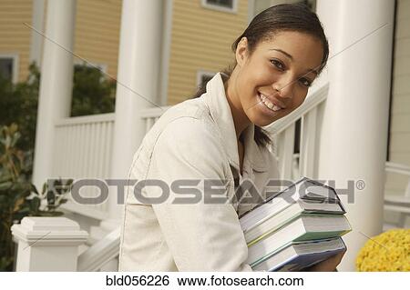 Stock Photograph - African woman carrying stack of books. Fotosearch