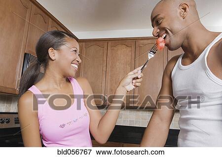 Stock Photo - African woman feeding fruit to husband. Fotosearch