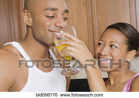 Stock Image - African woman holding juice glass for husband. Fotosearch