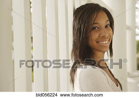 Picture - African woman leaning on porch railing. Fotosearch