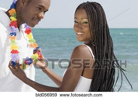 Stock Photo - African woman touching lei around husband’s neck. Fotosearch