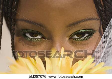 African woman with flower in front of face View Large Photo Image Stock Photograph - African woman with flower in front of face. Fotosearch