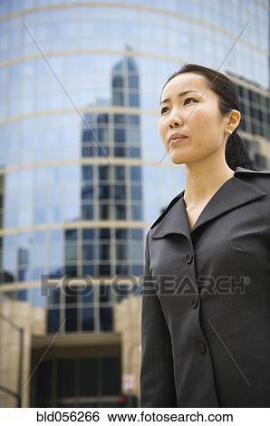 Stock Photograph - Asian businesswoman in front of high-rise. Fotosearch