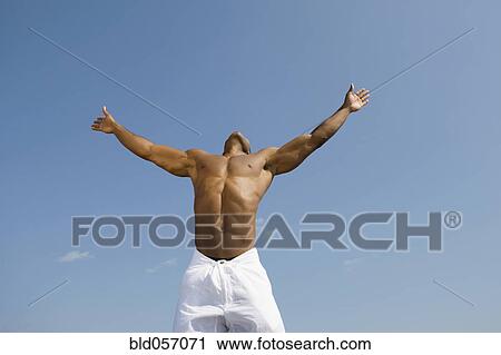Stock Image - Bare-chested man with arms outstretched. Fotosearch