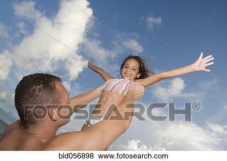 Stock Photo - Father holding daughter in air. Fotosearch