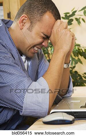 Stock Photography - Frustrated Pacific Islander man next to laptop. Fotosearch