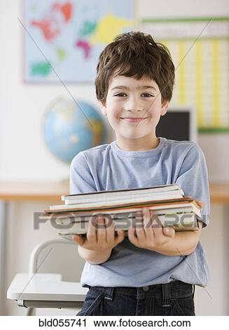 Hispanic boy holding stack of school books View Large Photo Image Stock Image - Hispanic boy holding stack of school books. Fotosearch