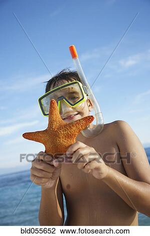 Stock Image - Hispanic boy holding starfish. Fotosearch