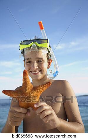 Stock Image - Hispanic boy holding starfish. Fotosearch