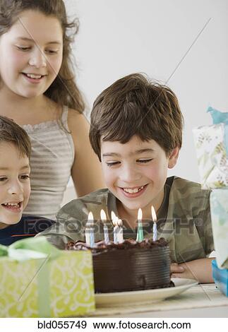 Stock Photo - Hispanic boy looking at birthday cake. Fotosearch